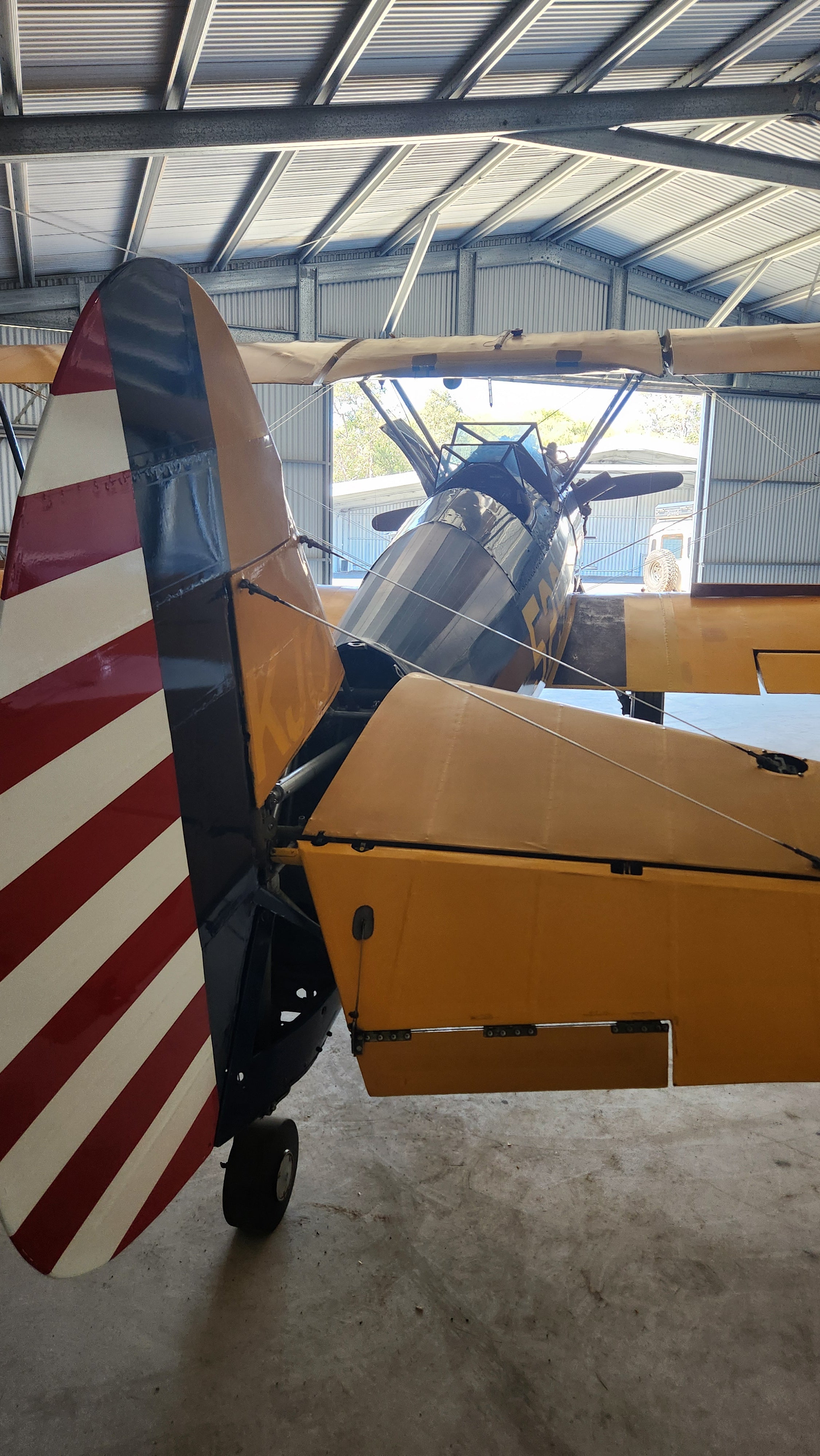 Boeing Stearman airplane with American flag design on tail inside a hangar