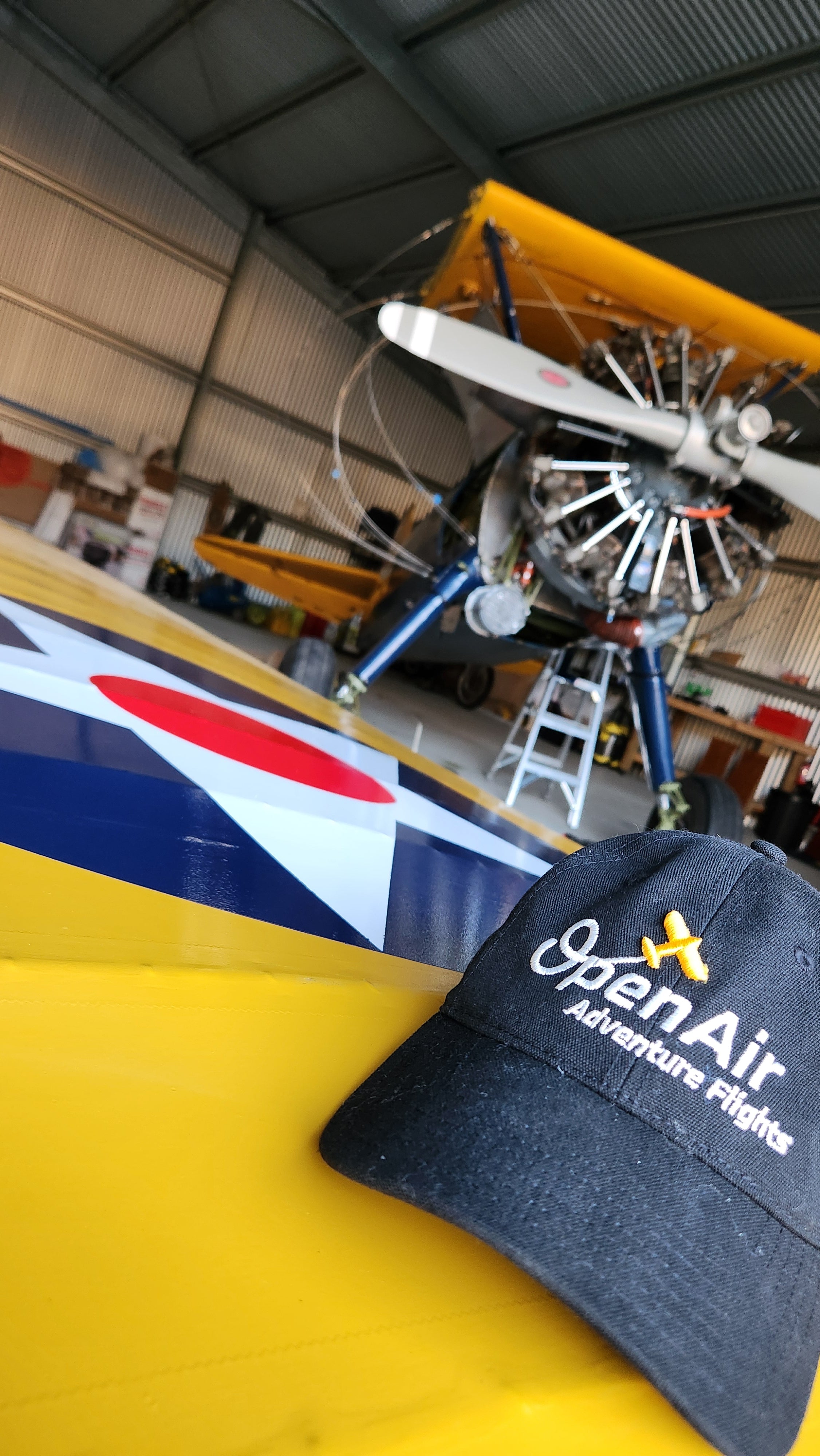 Open air adventure flights hat sitting on a freshly painted wing with their boeing stearman "winnie" in the background