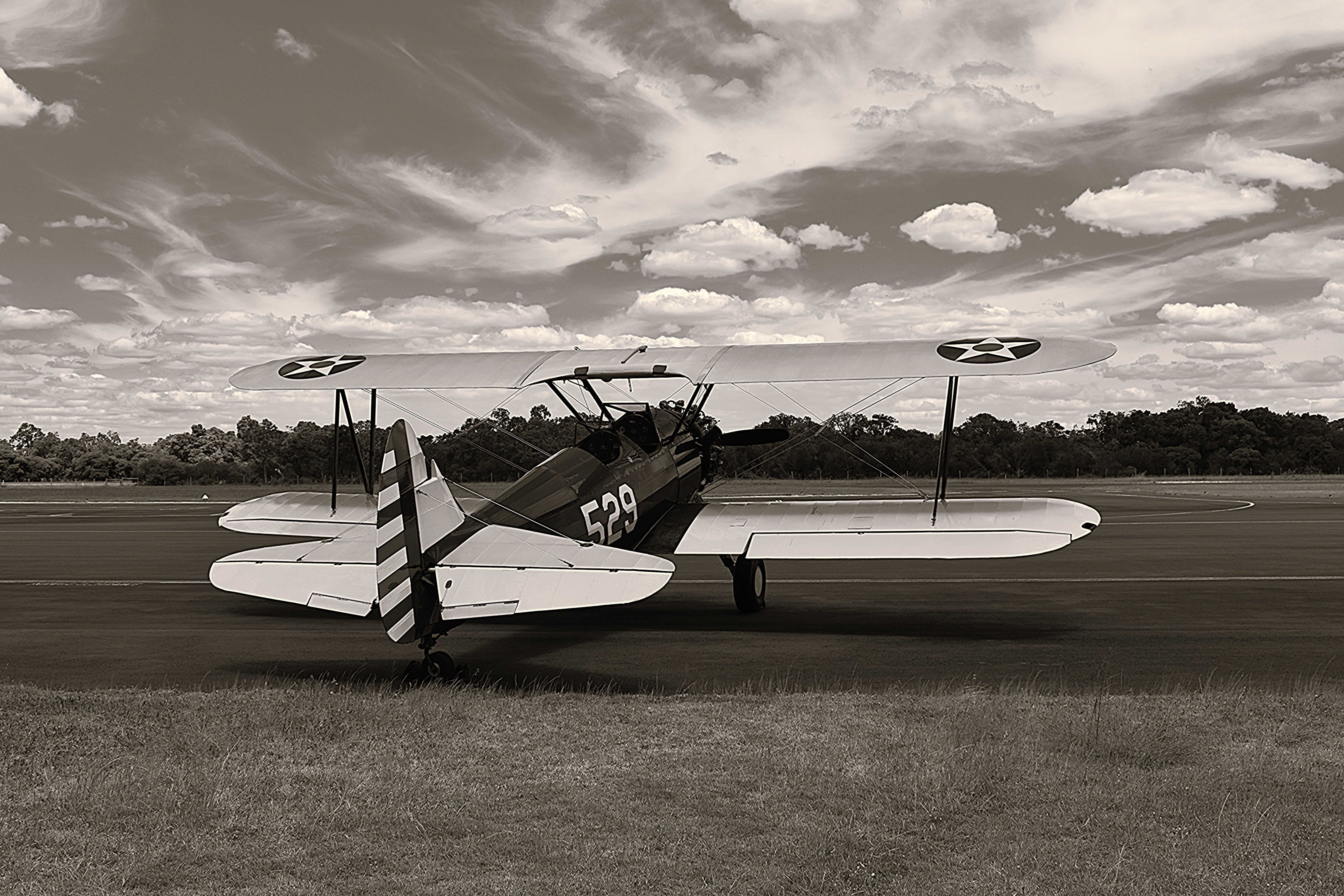 Vintage biplane on a runway with a cloudy sky in the background