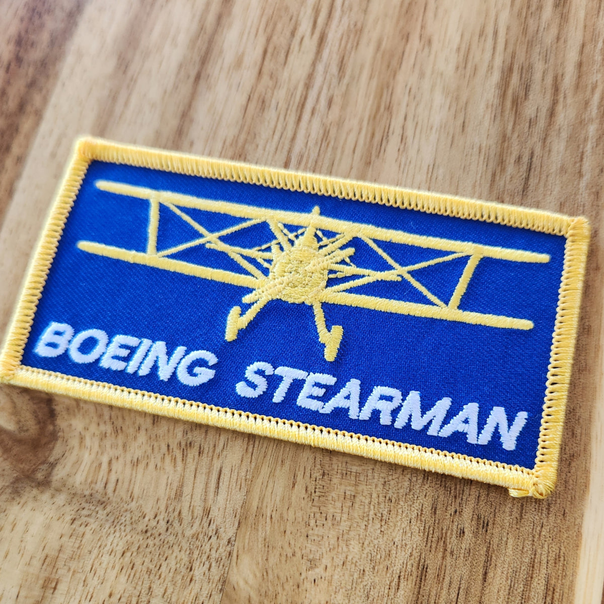 Rectangular Open Air Adventure Flights embroidered patch featuring a front-view Boeing Stearman silhouette and Boeing Stearman text, displayed on a wooden table.