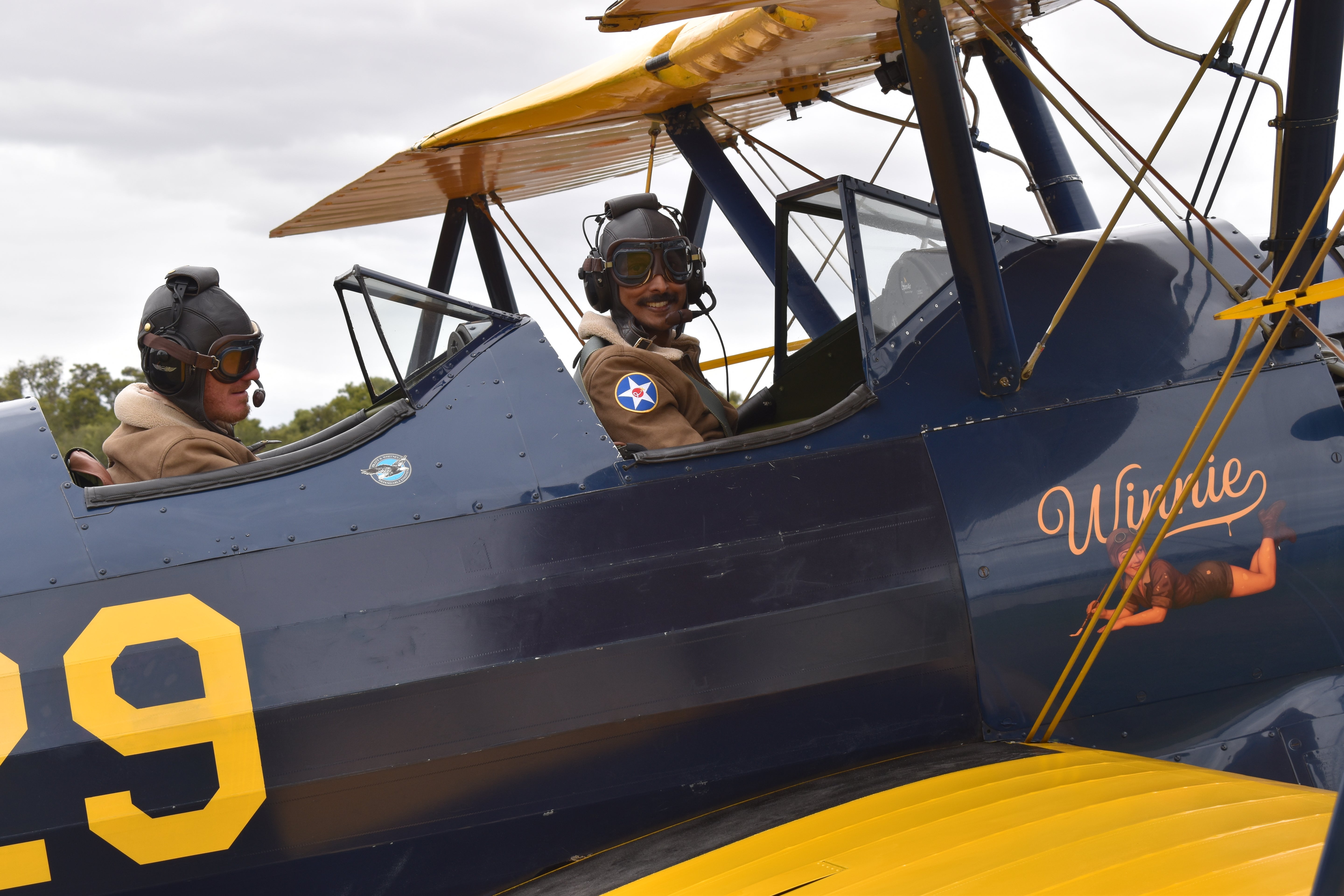 Happy passenger smiling in the front cockpit of Winnie, the 1941 Boeing Stearman, during an Open Air Adventure Flights experience in Bunbury.