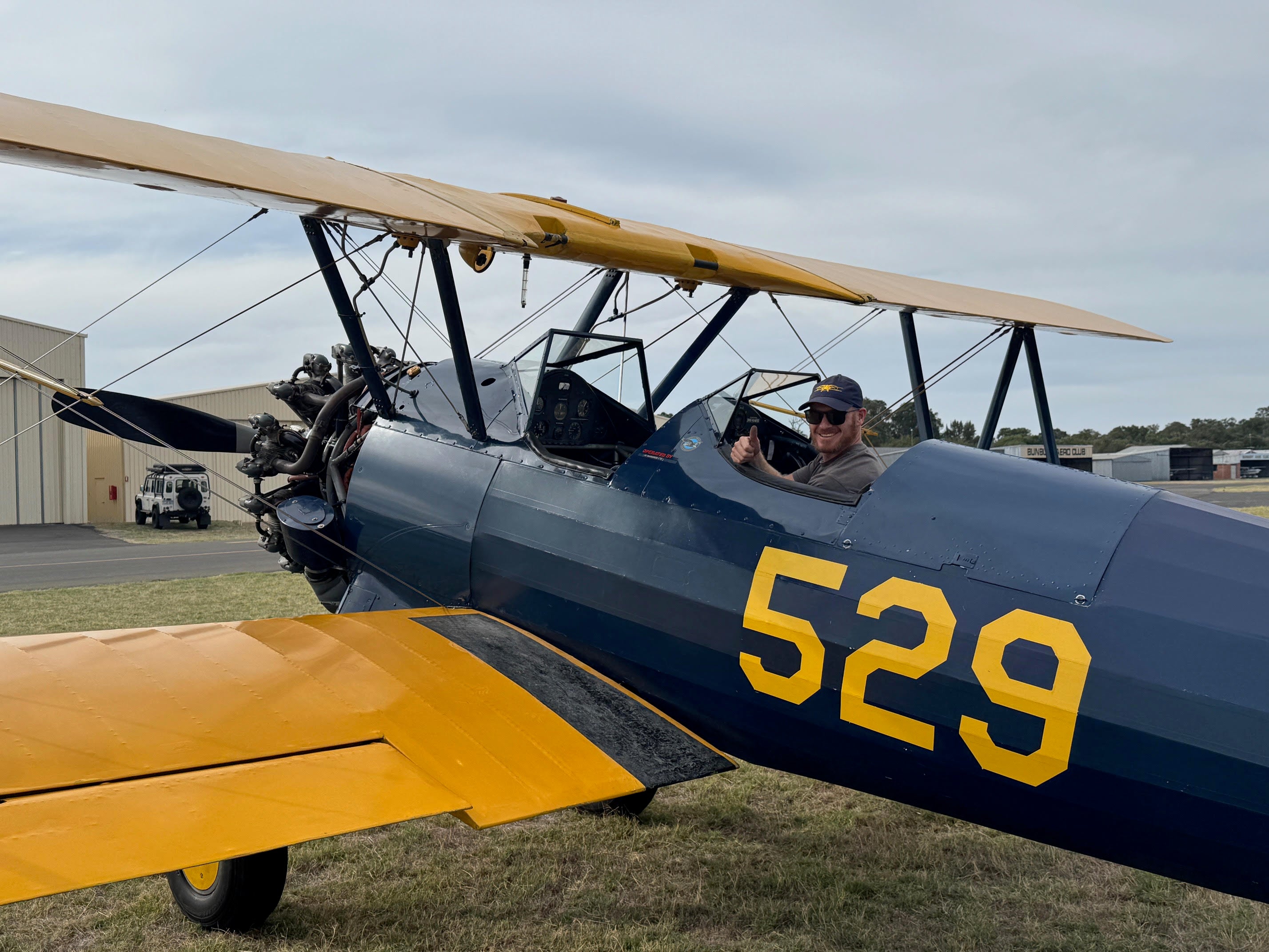 Johan Strydom sitting in the cockpit of Winnie during the restoration of the 1941 Boeing Stearman, giving a thumbs-up during the aircraft’s restoration journey in Bunbury Western Australia.