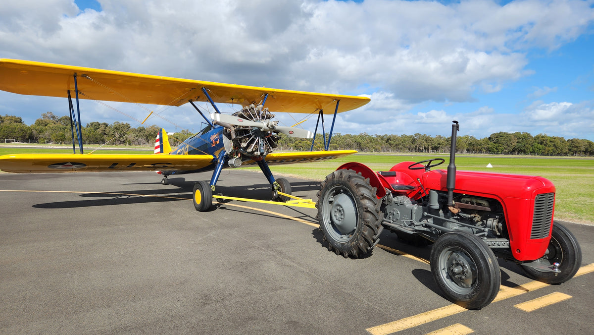 Lex, the vintage Ferguson 35 tractor, towing Winnie, Open Air Adventure Flights’ 1941 Boeing Stearman biplane, at Bunbury Airport.
