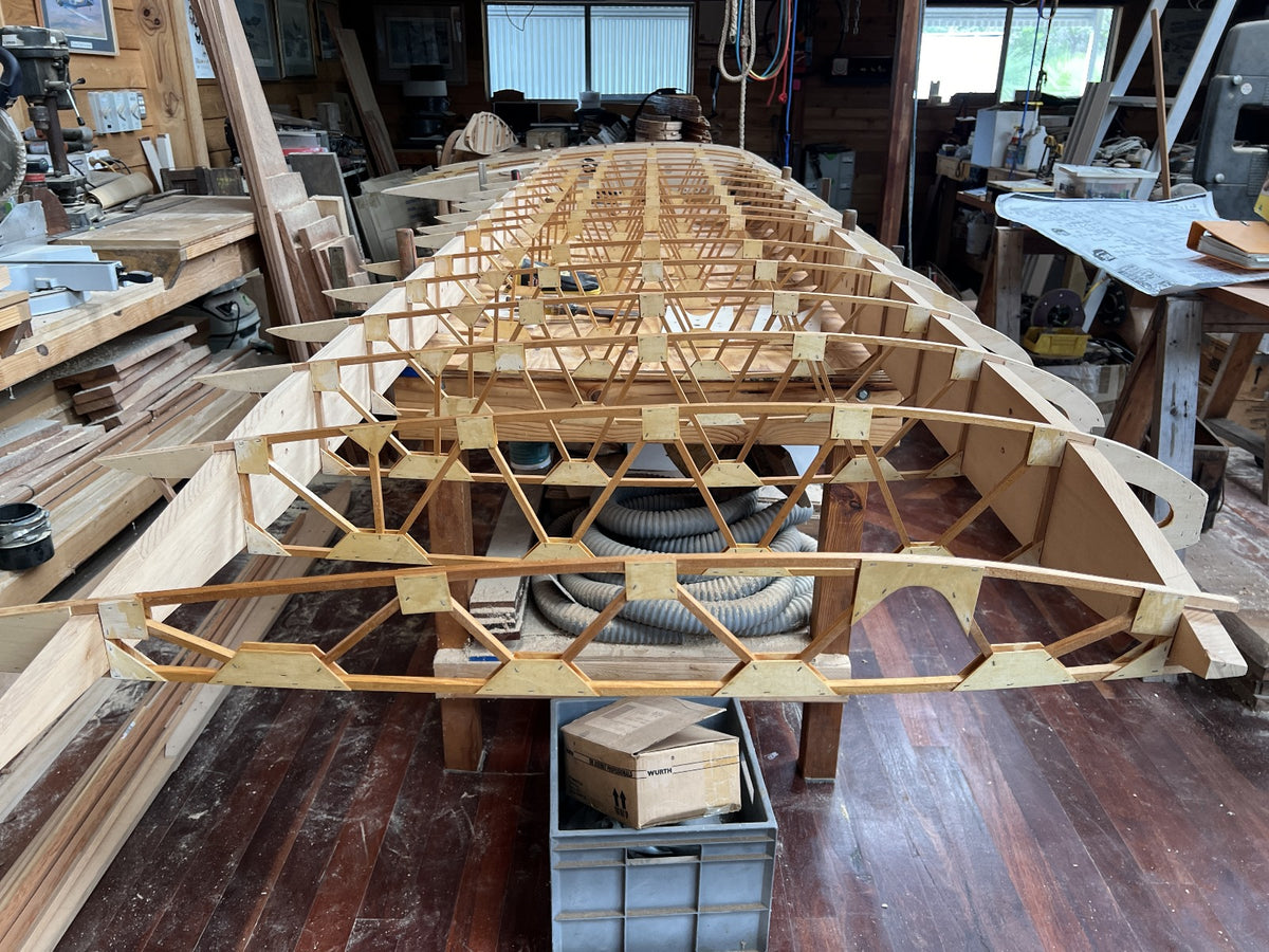 Detailed view of a hand-crafted wooden wing rib structure for a classic aircraft under construction in a workshop.
