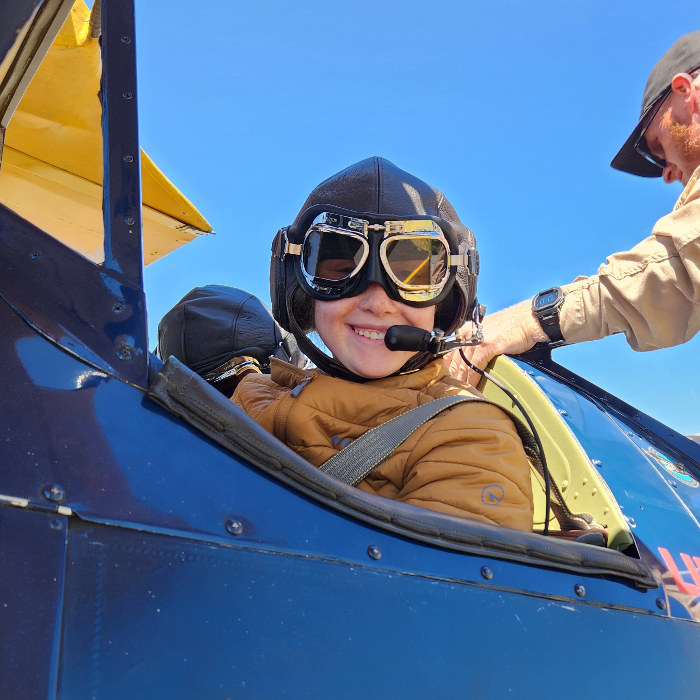 Young girl sitting in the front cockpit of Winnie, the 1941 Boeing Stearman, before an Open Air Adventure Flights experience in Bunbury.